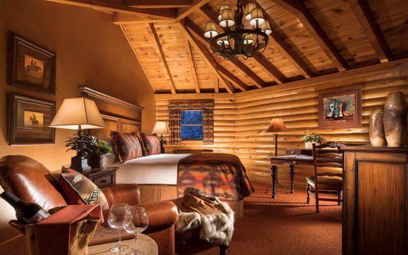 luxury hotel cabin with king bed and wooden log ceiling and walls