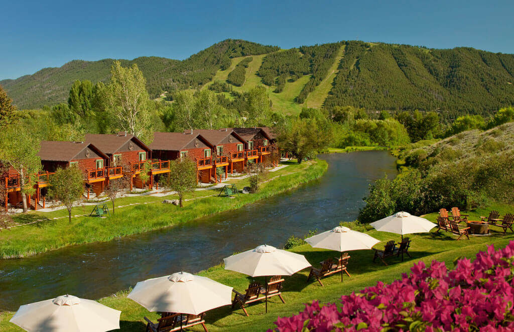 cabins along river in summer time with umbrella tables in forefront