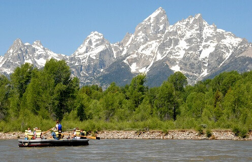 group of people on scenic float trip on river with mountain in background