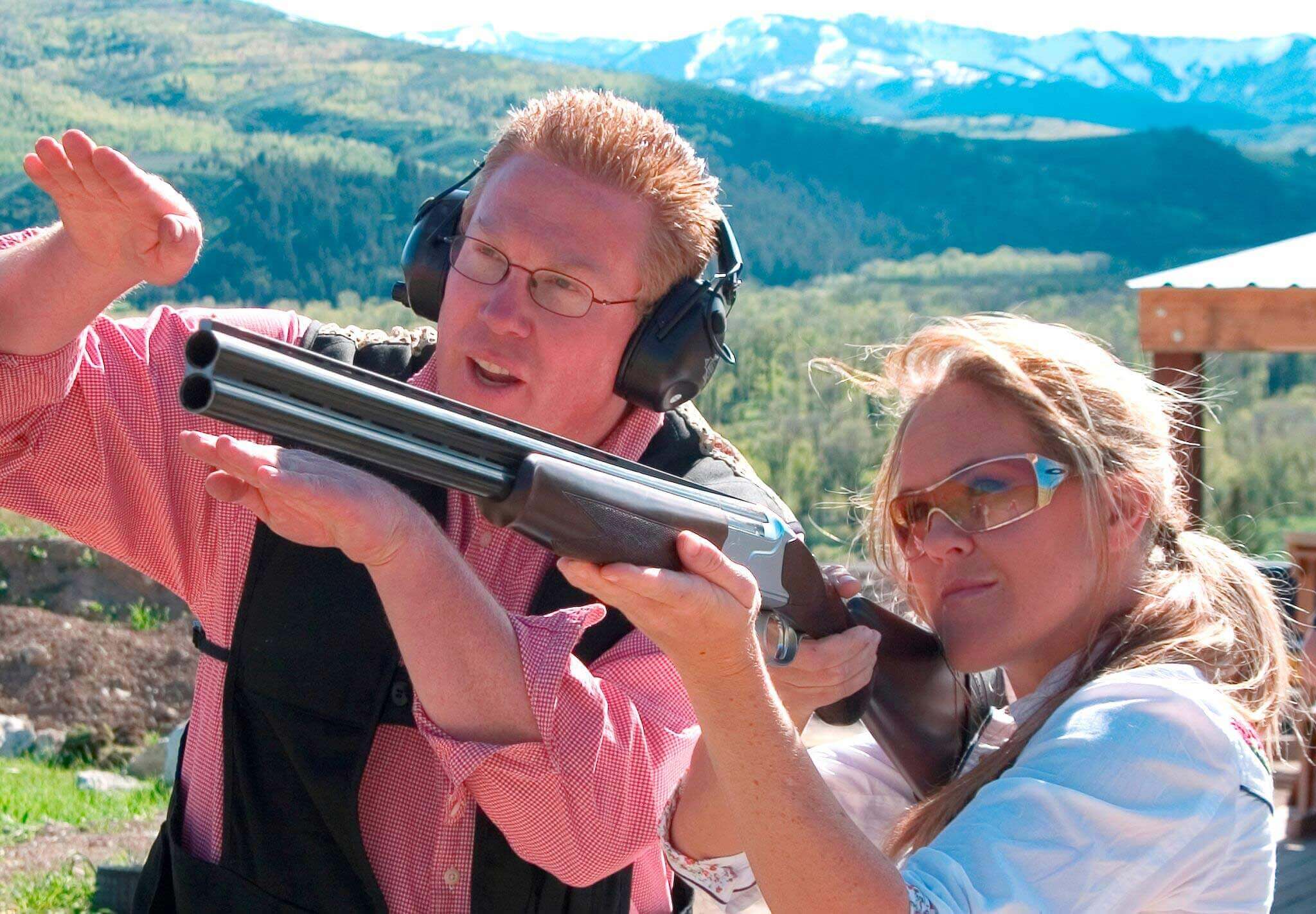 male instructor teaching a woman how to shoot a rifle