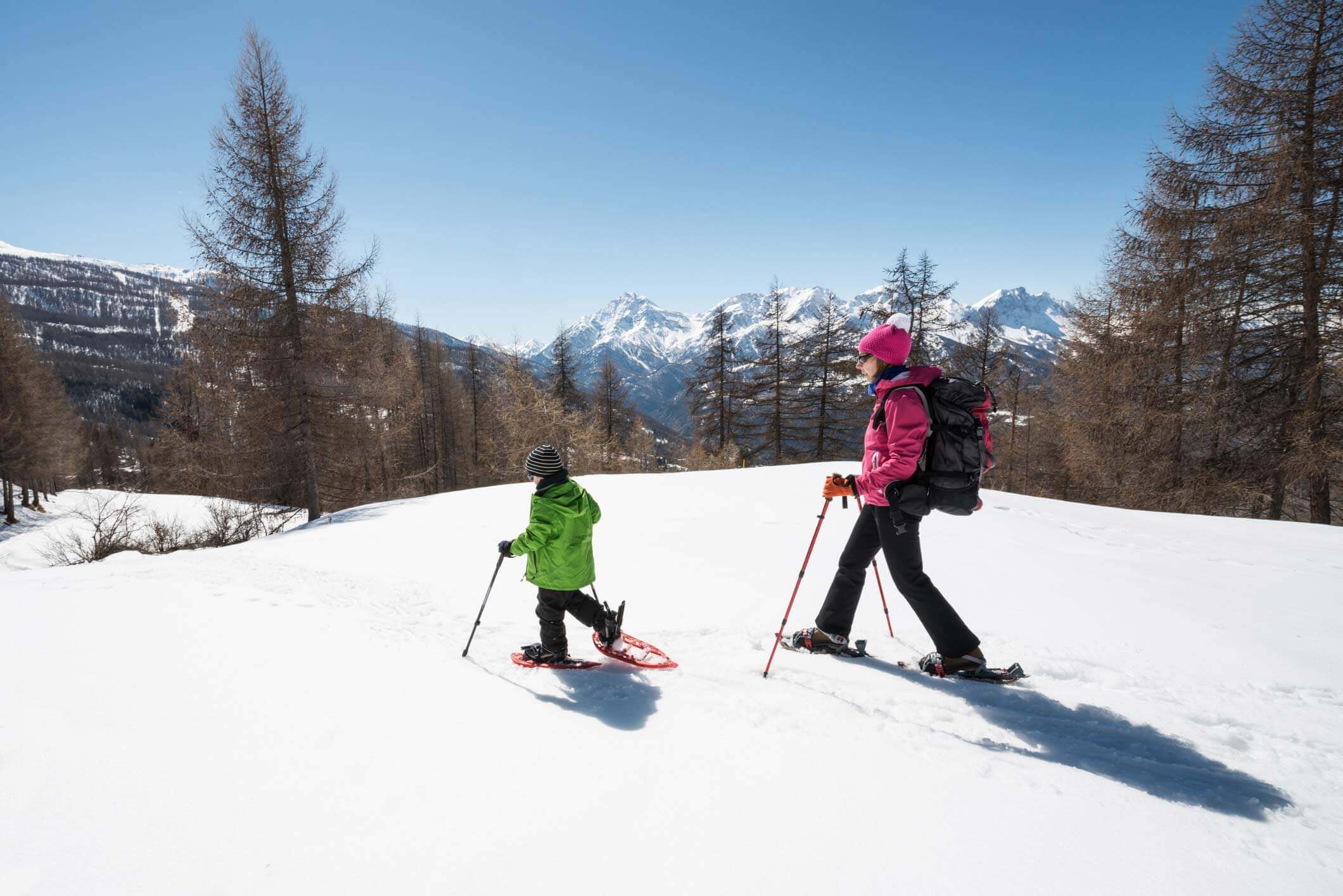 Mother and child snowshoeing through the woods and mountains