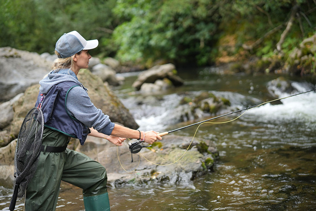 young woman fly fishing in a mountain river